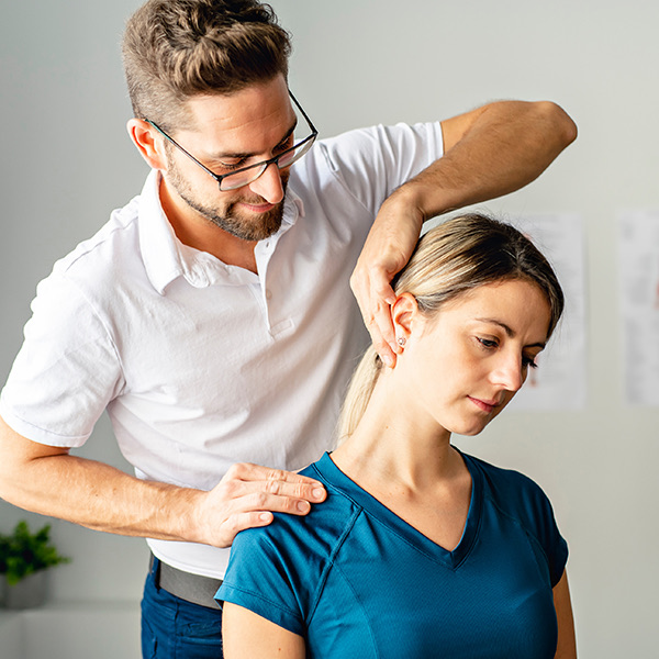 Therapeut führt Kopf und Schulter einer Patientin bei einer PNF-Bewegung